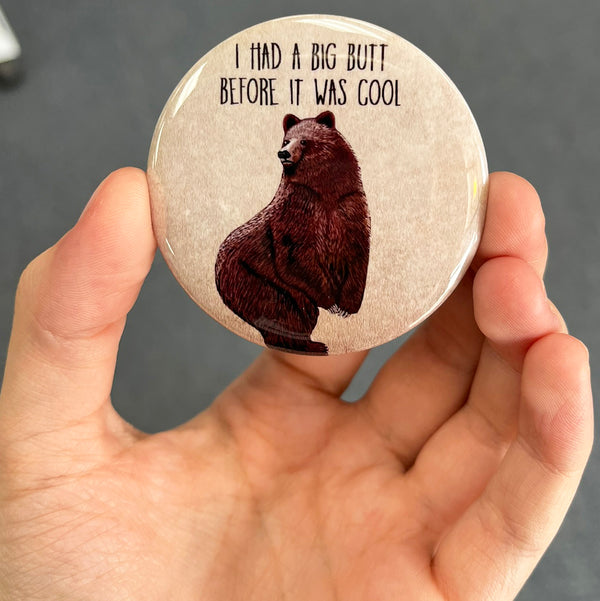 Funny bear magnet held in hand to show 2.25-inch size and glossy finish