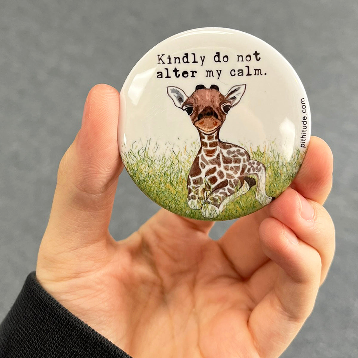 Calm giraffe magnet held in hand to show 2.25-inch size and glossy finish