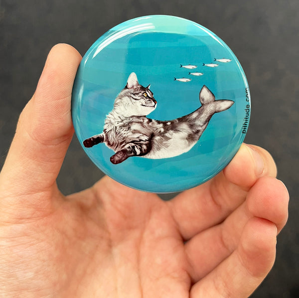 Whimsical cat mermaid magnet held in hand to show 2.25-inch size and glossy finish