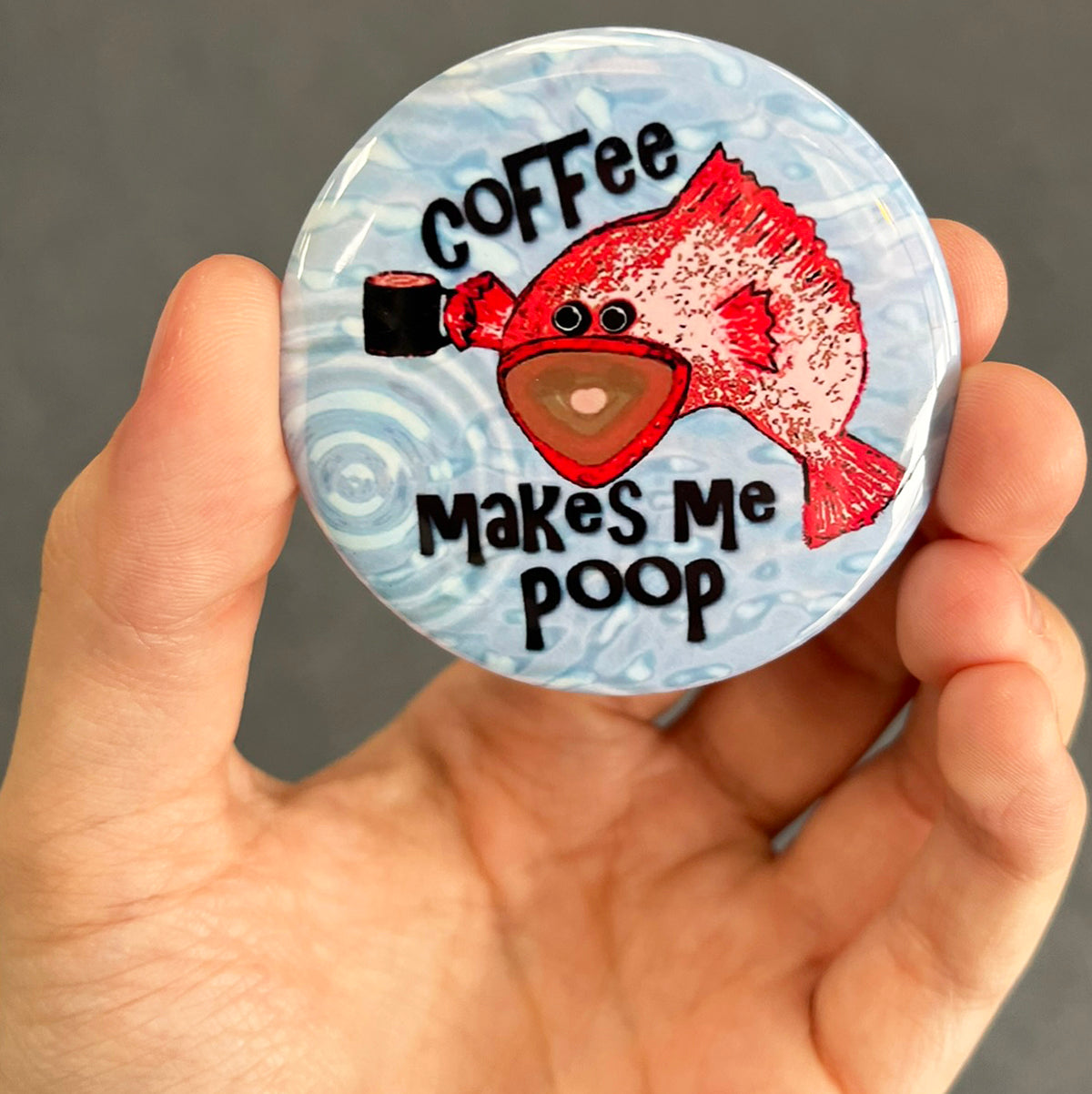 Funny coffee magnet held in hand to show 2.25-inch size and glossy finish
