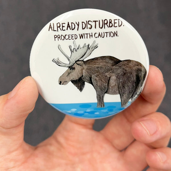 Funny moose magnet held in hand to show 2.25-inch size and glossy finish