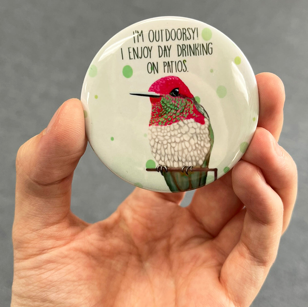 Funny patio drinking magnet held in hand to show 2.25-inch size and glossy finish