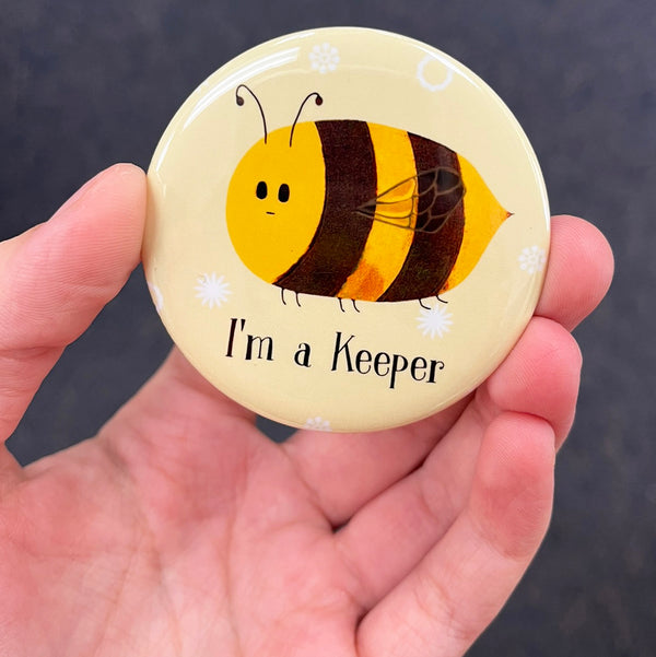 Funny beekeeper magnet held in hand to show 2.25-inch size and glossy finish