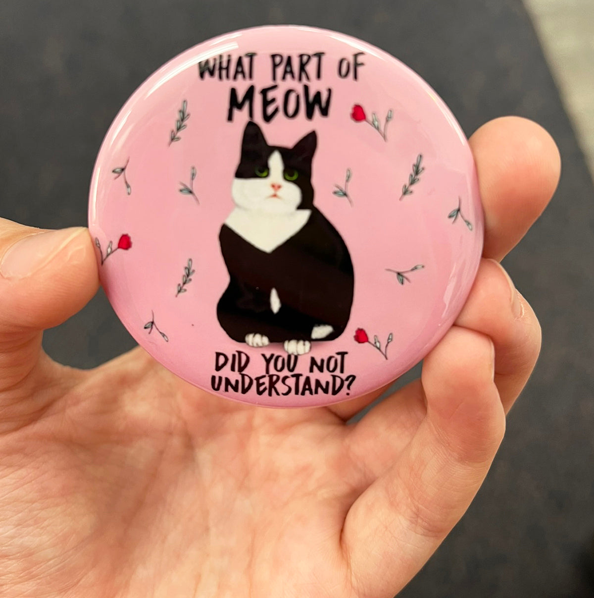 Funny tuxedo cat magnet held in hand to show 2.25-inch size and glossy finish