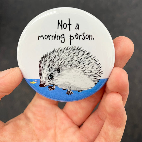 Funny hedgehog magnet held in hand to show 2.25-inch size and glossy finish