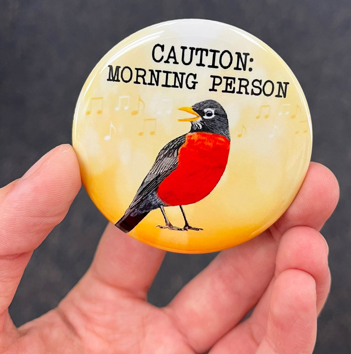 Funny morning person magnet held in hand to show 2.25-inch size and glossy finish