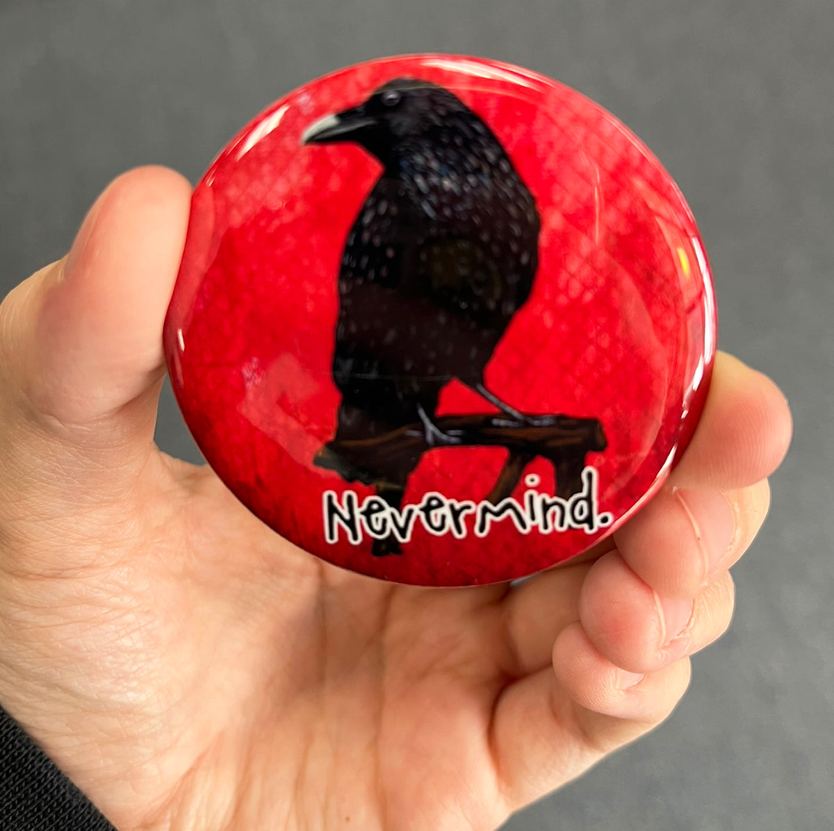 Funny raven magnet held in hand to show 2.25-inch size and glossy finish