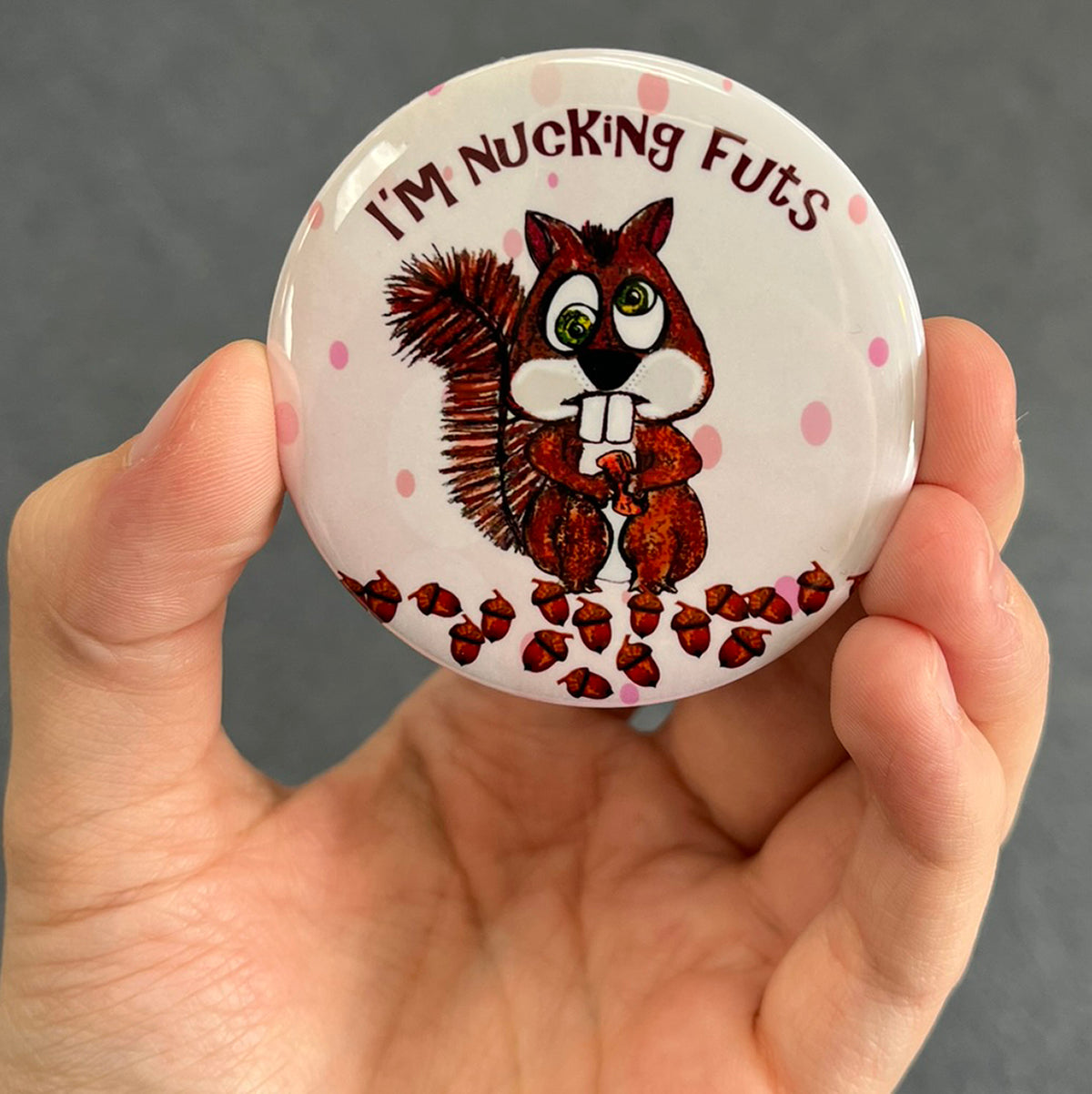Funny squirrel magnet held in hand to show 2.25-inch size and glossy finish