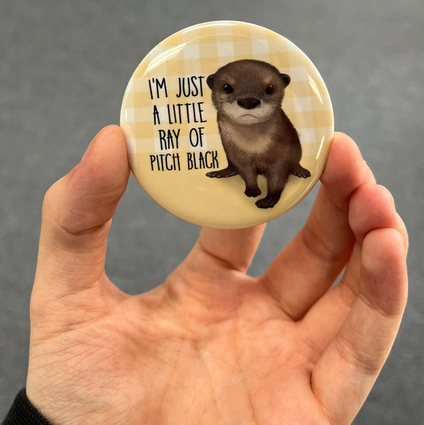 Funny sea otter magnet held in hand to show 2.25-inch size and glossy finish