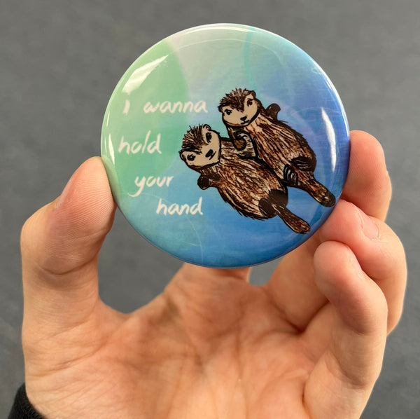 Romantic sea otter magnet resting in an open palm with glossy finish visible