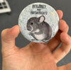 Funny work magnet held in hand to show 2.25-inch size and glossy finish