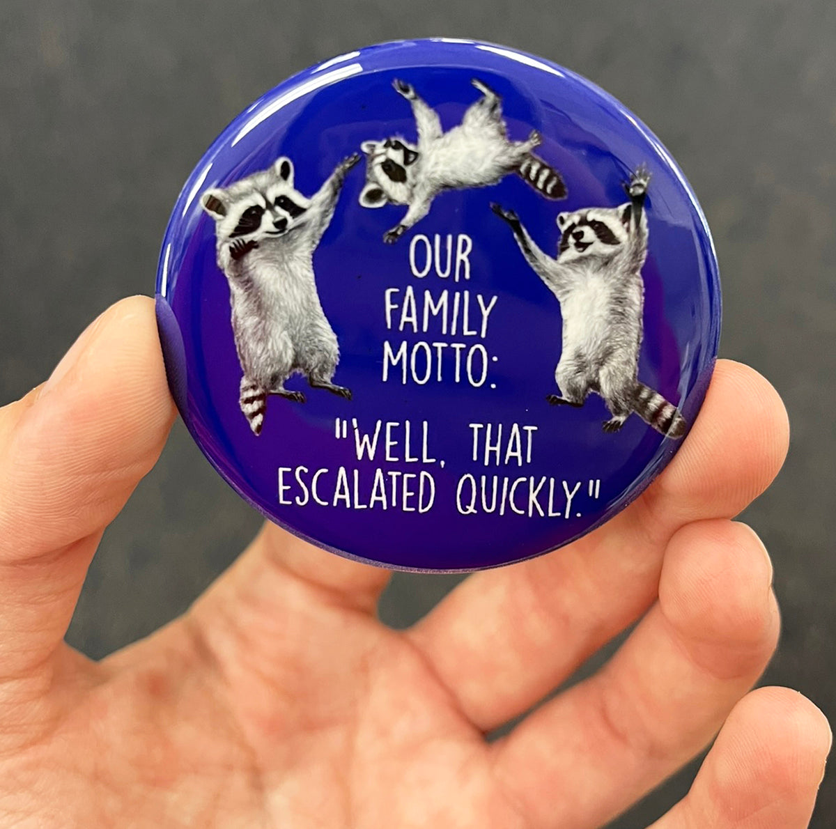 Funny raccoon family magnet held in hand to show 2.25-inch size and glossy finish