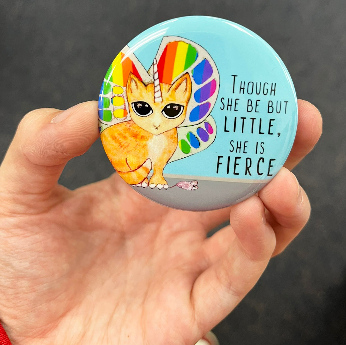Rainbow unicorn cat magnet held in hand to show 2.25-inch size and glossy finish