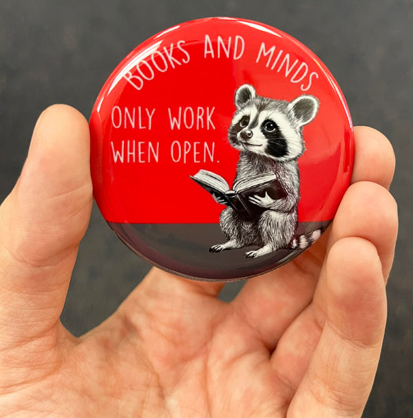 Book lover raccoon magnet held in hand to show 2.25-inch size and glossy finish