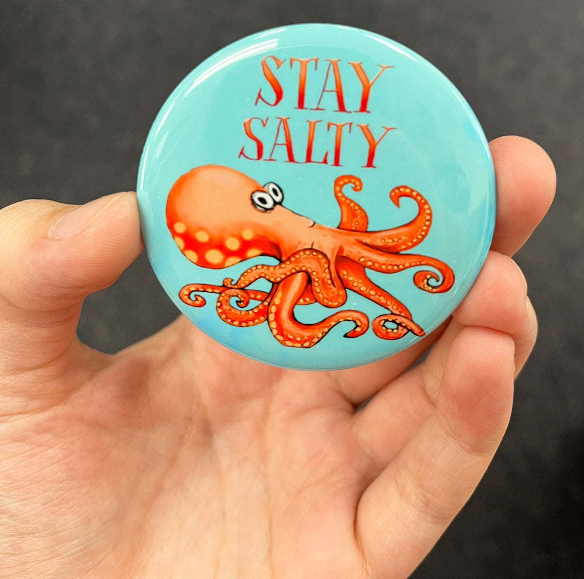 Funny octopus magnet held in hand to show 2.25-inch size and glossy finish
