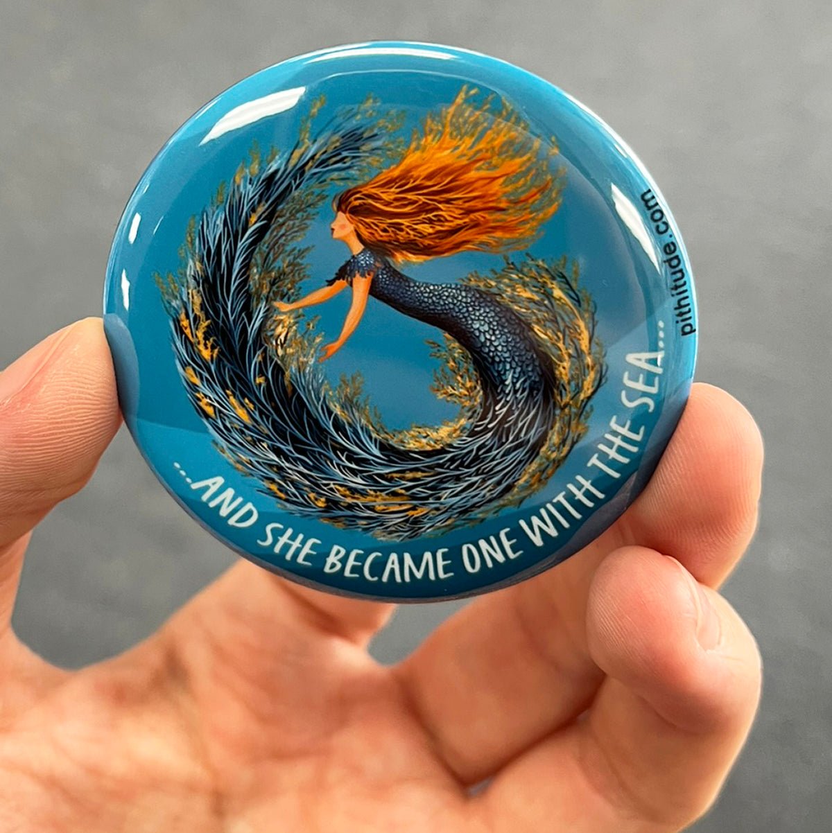 Whimsical mermaid magnet held in hand to show 2.25-inch size and glossy finish