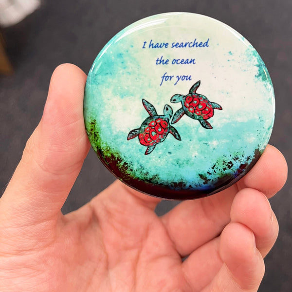 Romantic sea turtle magnet held in hand to show 2.25-inch size and glossy finish