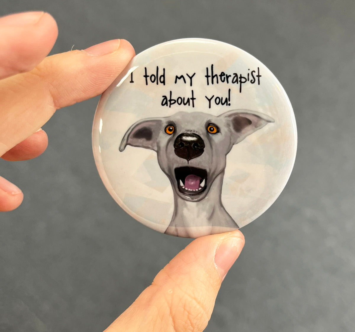 Funny dog magnet held in hand to show 2.25-inch size and glossy finish