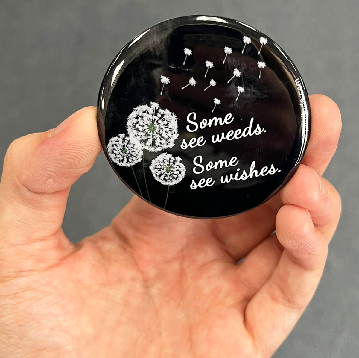 Inspirational dandelion magnet held in hand to show 2.25-inch size and glossy finish