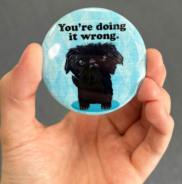 Funny dog magnet held in hand to show 2.25-inch size and glossy finish